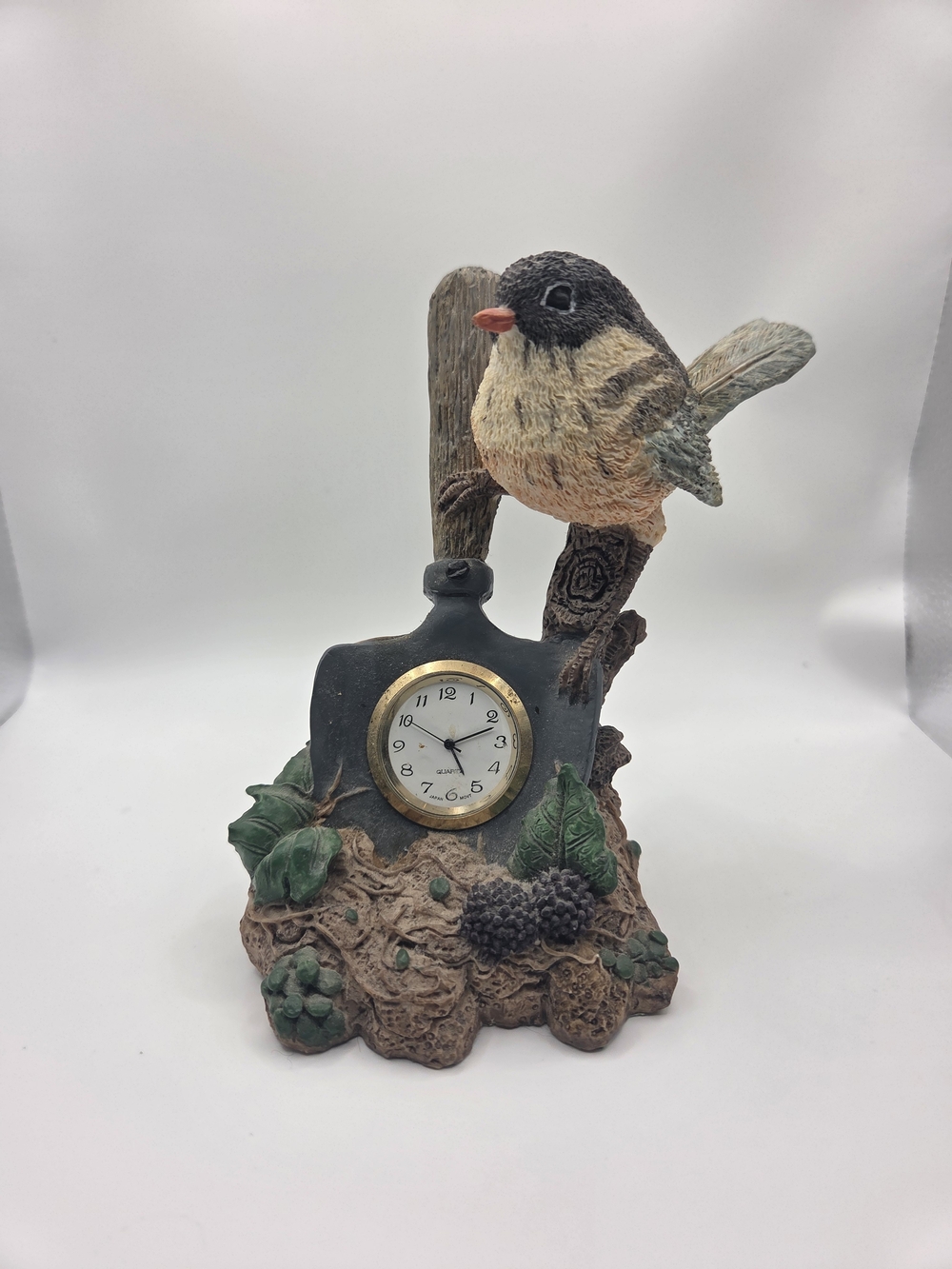 Vintage resin desk clock with a bird perched on a shovel handle